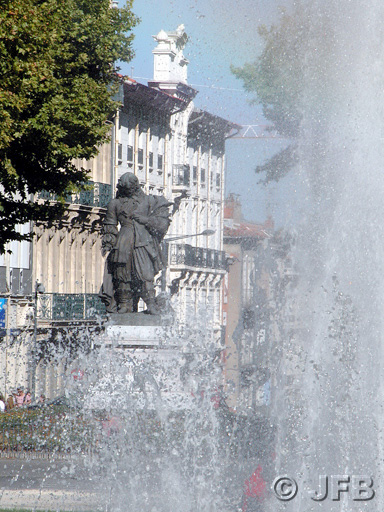 Statue de Paul Riquet, vue verticale. Au premier plan, un jet d'eau, et dans le fond, la statue