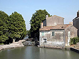 A droite, les bâtiments de l'écluse et les vieux moulins, au centre, le canal file droit, on aperçoit deux vannes de la quadruple écluse de Saint-Roch.