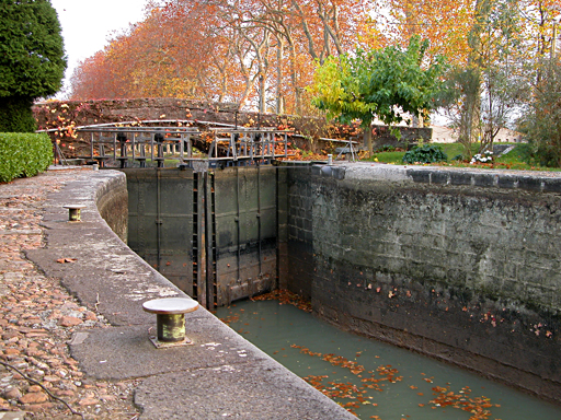 Magnifiques couleurs d'automne sur l'&eacute;cluse dont on aper?oit une vanne et une partie du bassin &agrave; son niveau le plus bas. &agrave; droite, un petit arbre poss&egrave;de encore de belles feuilles vert tendre
