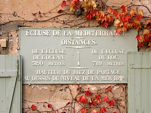Panneau des distances à l'écluse de la Méditerranée. Couleurs d'automne, feuilles rouges sur le mur
